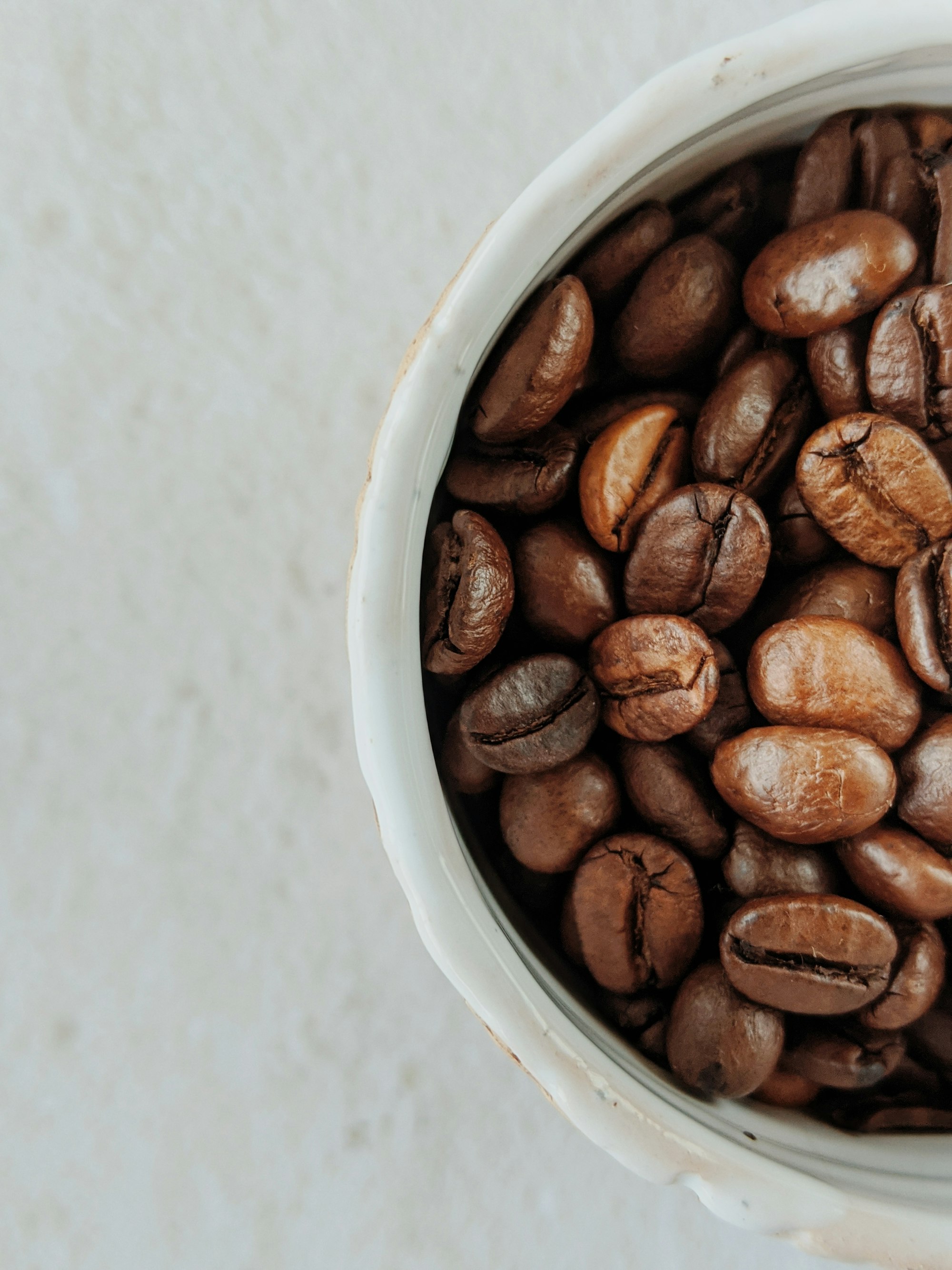 Roasted coffee beans in a white porcelain bowl