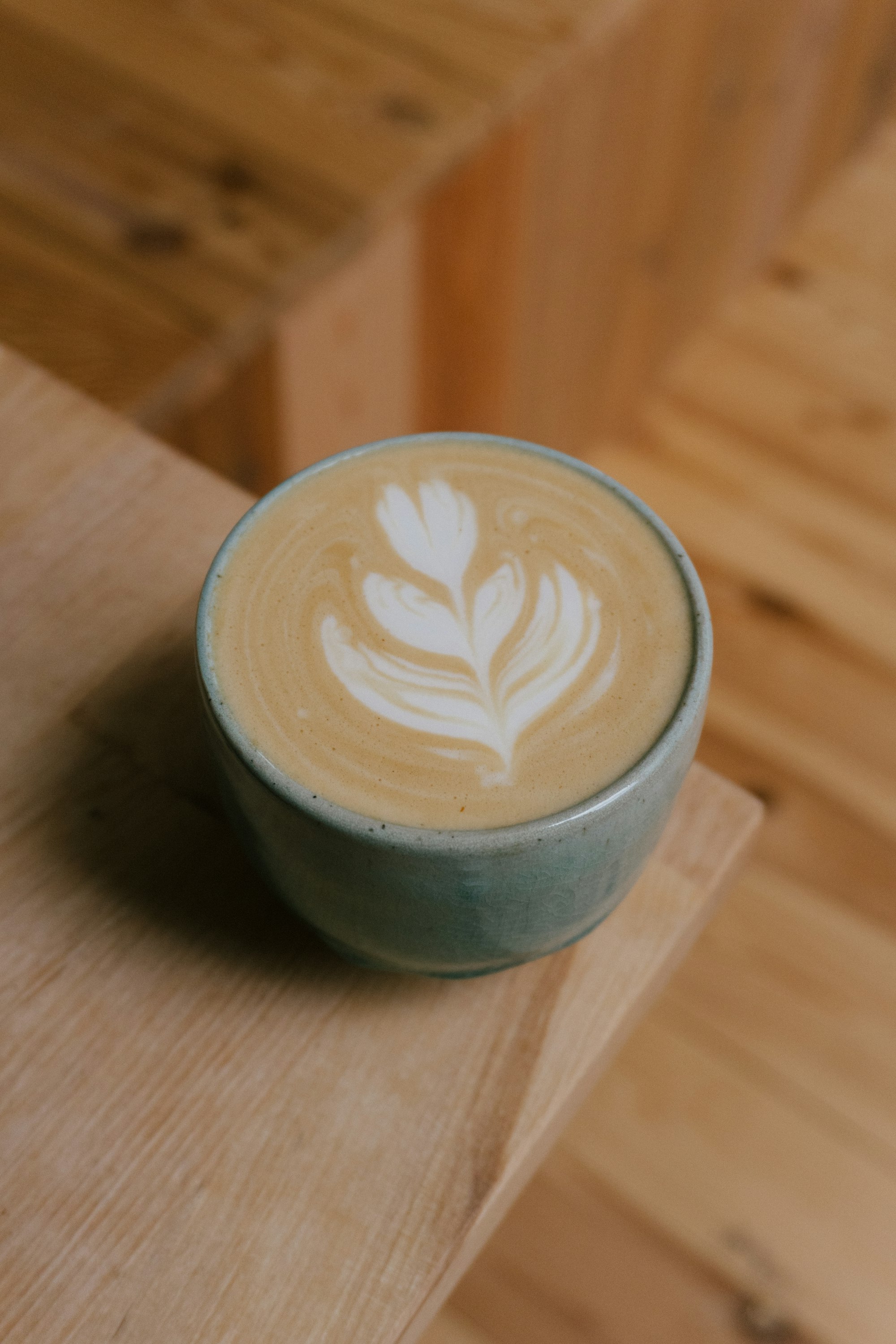 Cappuccino with rosetta latte art on a wooden table