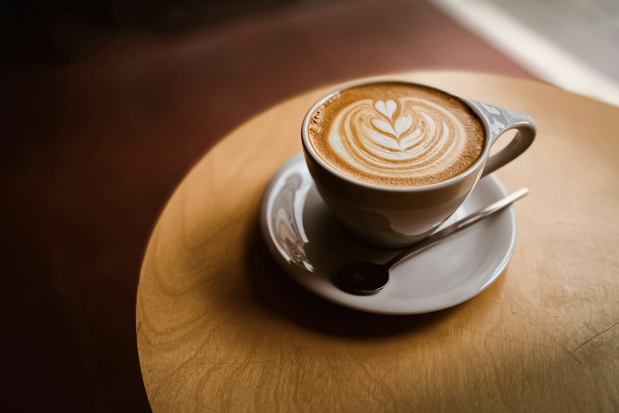 Flat white with tulip latte art on a round wooden table
